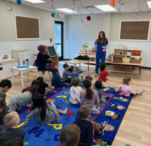 Pediatric dental team member reading with children on a colorful rug