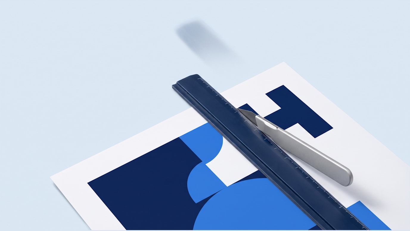 A printed poster is being cropped with a ruler sliding across its edge