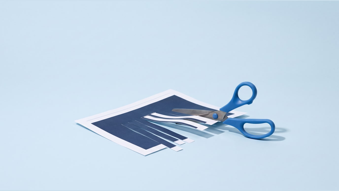 A printed article is being cut into smaller strips with scissors