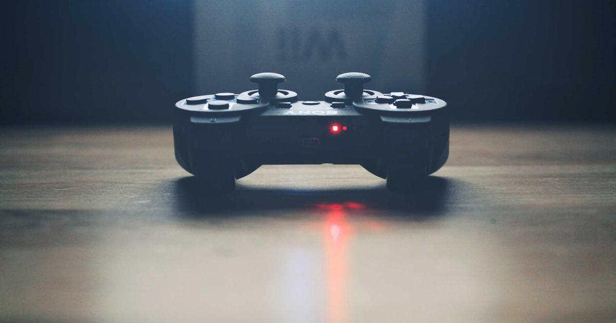 A DualSense controller resting on a wooden desk